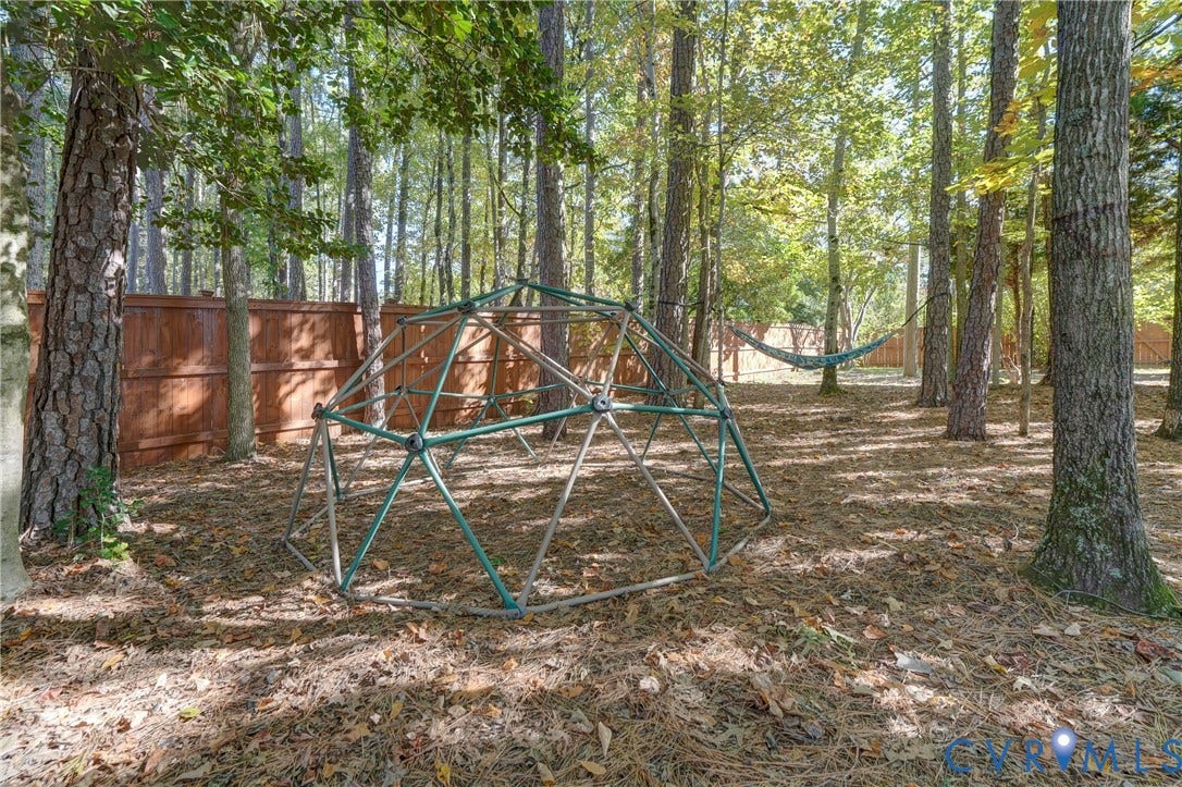 5 Bridgehampton Place, Yorkshire, Henrico, VA 23229 Wooded backyard featuring a perimeter wood privacy fence, mature trees, and a metal climbing dome