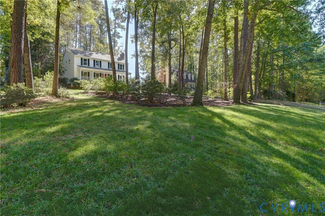 5 Bridgehampton Place, Yorkshire, Henrico, VA 23229 Expansive grass lawn featuring mature trees and established landscaping surrounding a two-story exterior with a covered front porch and multi-pane windows