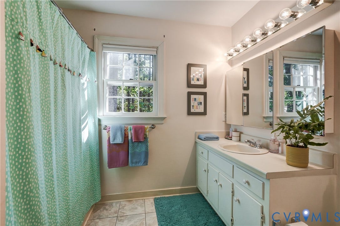 5 Bridgehampton Place, Yorkshire, Henrico, VA 23229 Bathroom featuring a light-toned vanity with an integrated basin, a tri-fold medicine cabinet, a multi-bulb vanity light fixture, and a window with a paneled design