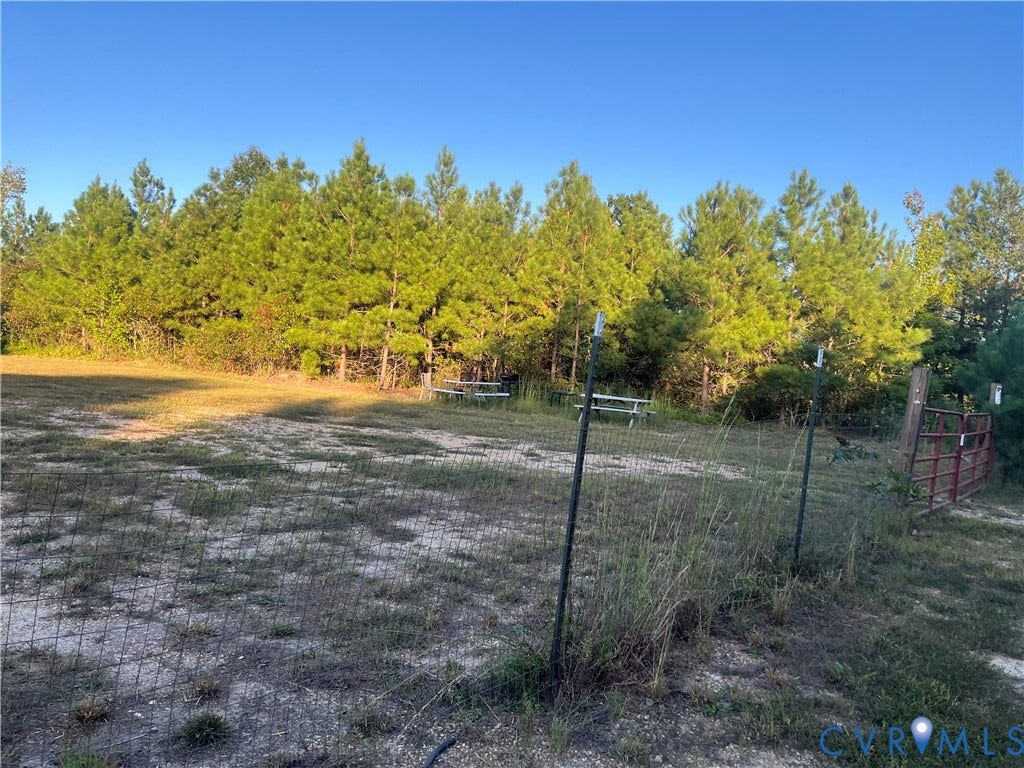 684 Verdon Road, Beaverdam, VA 23015 Open acreage featuring wire mesh fencing, a metal gate, and a tree-lined perimeter