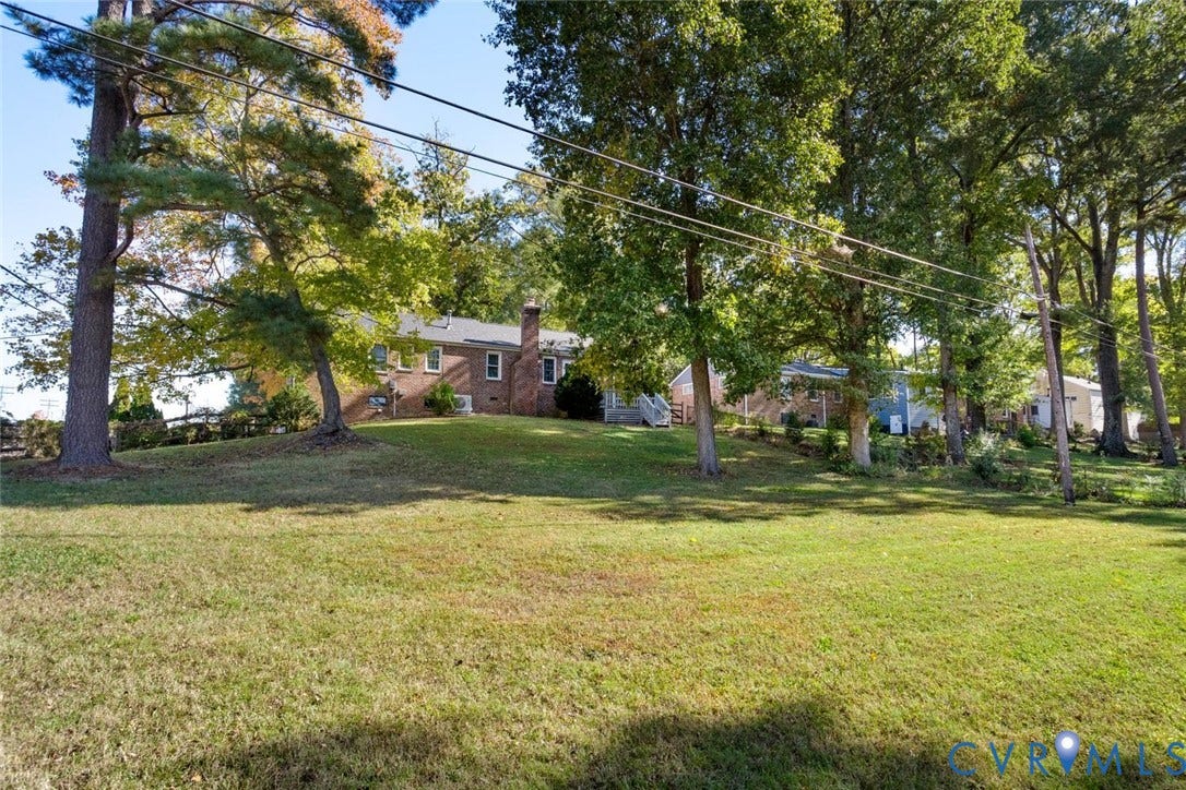 1014 Westbriar Drive, Henrico, VA 23238 Expansive lawn featuring mature trees and a brick exterior with a prominent chimney