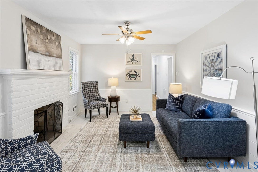 1014 Westbriar Drive, Henrico, VA 23238 White painted brick fireplace, light-toned wood-finish flooring, half-wall wainscoting, and a multi-blade ceiling fan with integrated lighting