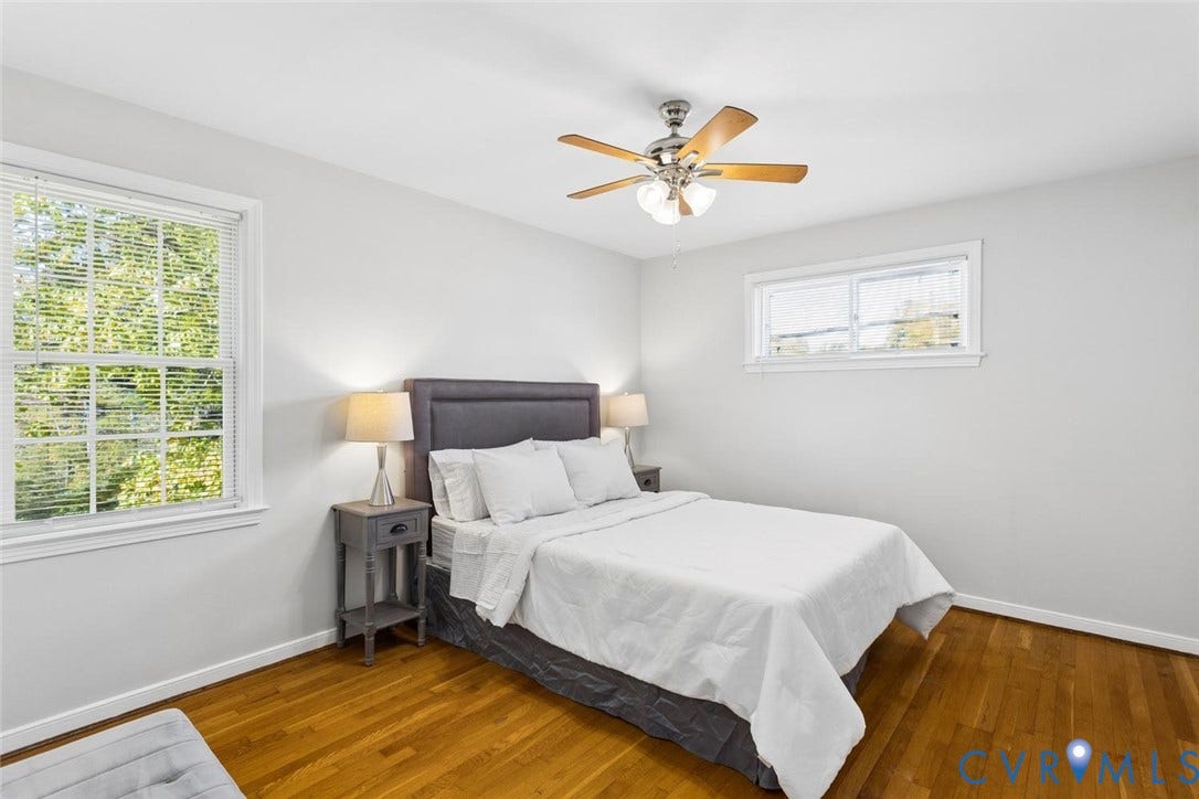 1014 Westbriar Drive, Henrico, VA 23238 Bedroom interior featuring wood-finish flooring, neutral wall paint, two double-hung windows, and a brushed metal ceiling fan with integrated light fixture