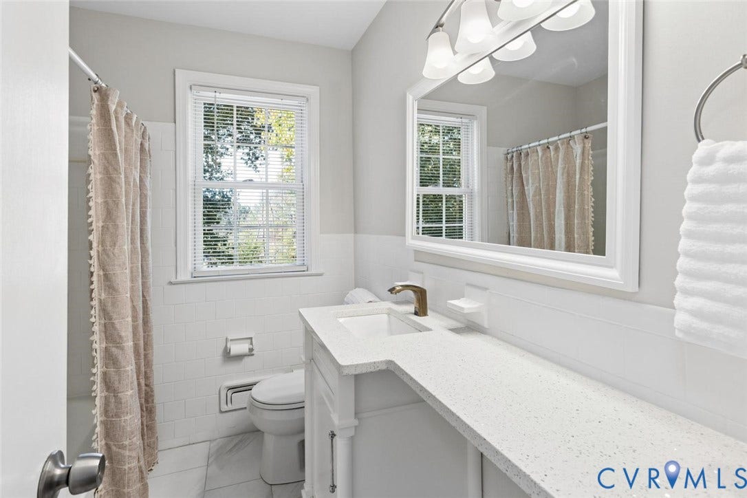 1014 Westbriar Drive, Henrico, VA 23238 Bathroom featuring a vanity with a white composite countertop, an integrated rectangular sink, a metallic faucet, a large framed mirror, and white subway-style wall tiling