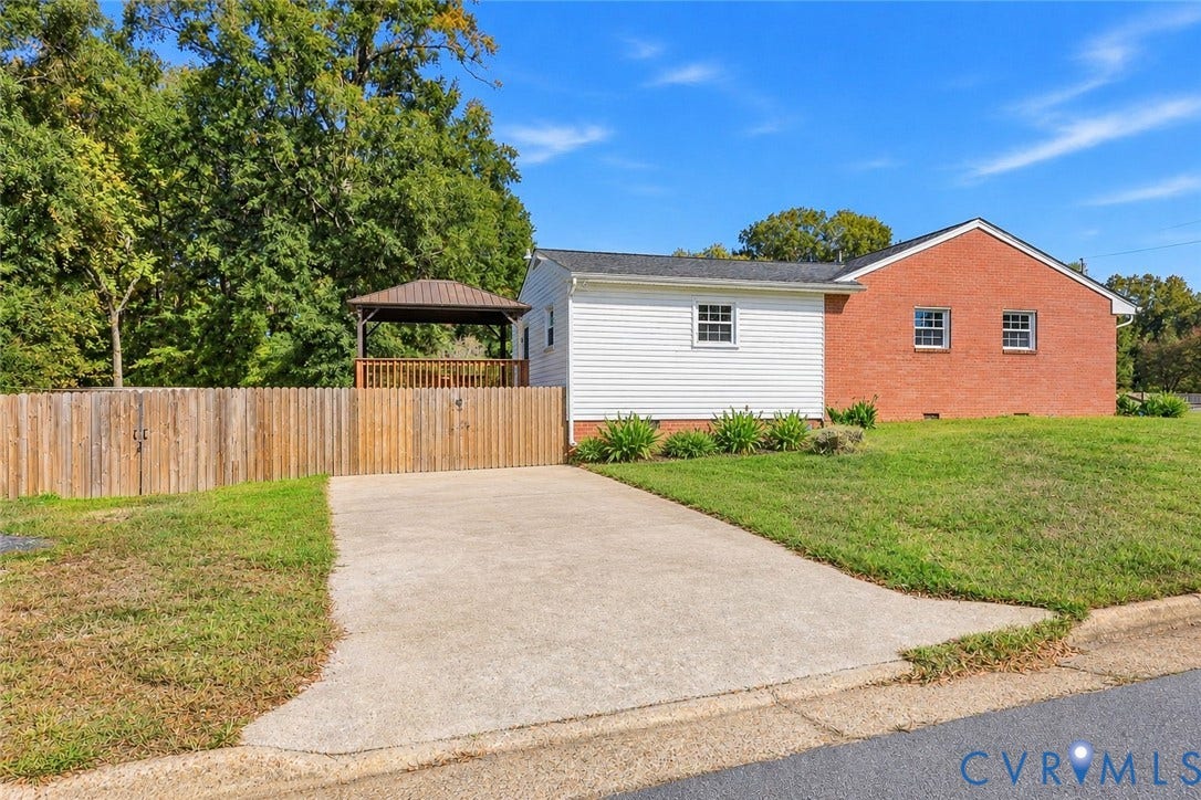 628 Ryan Avenue, Ryan, Colonial Heights, VA 23834 Exterior facade featuring red brick and white siding, concrete driveway, vertical wood privacy fencing, and a detached wooden gazebo