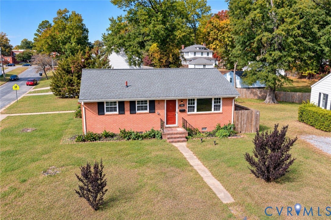 628 Ryan Avenue, Ryan, Colonial Heights, VA 23834 Red brick exterior featuring a shingle roof, decorative shutters, a central entrance with wrought iron railing, and concrete walkway