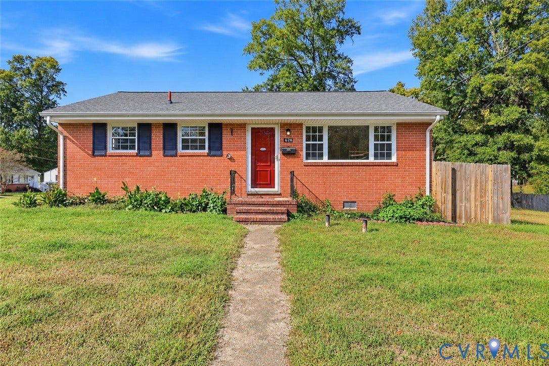 628 Ryan Avenue, Ryan, Colonial Heights, VA 23834 Single-story brick exterior featuring a shingled hip roof, dark shutter accents, a central red entry door, and a wooden privacy fence