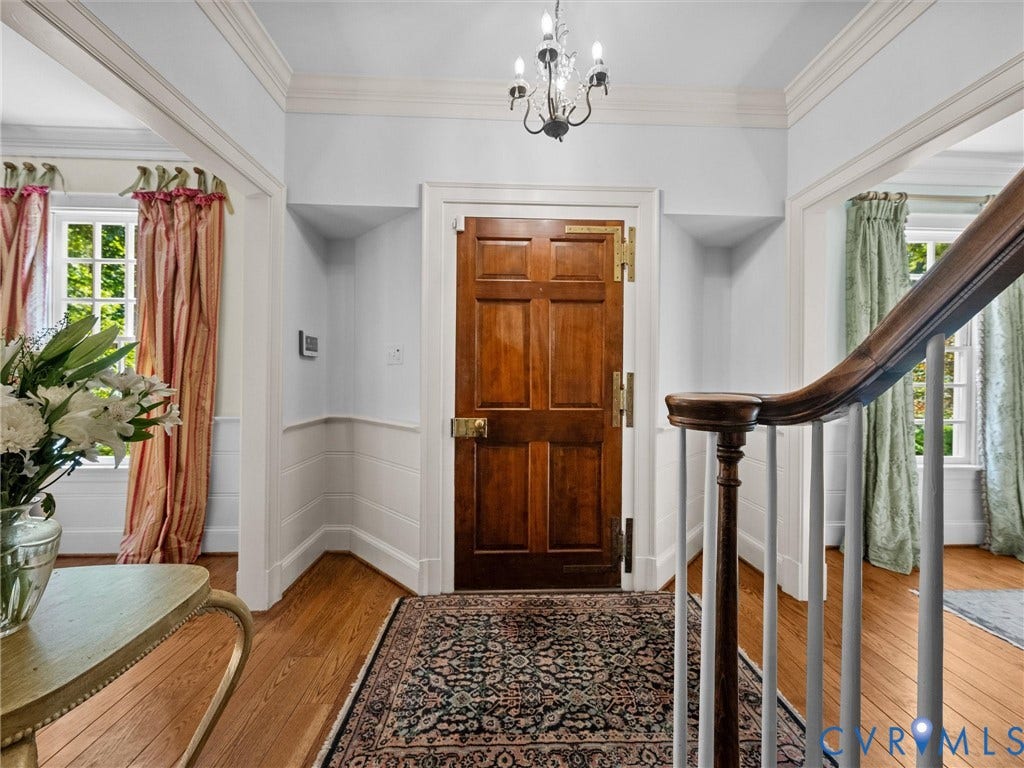 105 Running Cedar Lane, Countryside, Henrico, VA 23229 Entryway featuring a six-panel wood door with brass hardware, wood-finish flooring, crown molding, wainscoting, and a multi-light chandelier