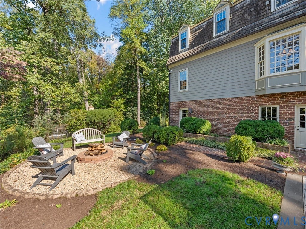 105 Running Cedar Lane, Countryside, Henrico, VA 23229 Brick and siding exterior featuring a multi-level roofline, circular fire pit area with stone edging, gravel patio surface, and landscaped garden beds