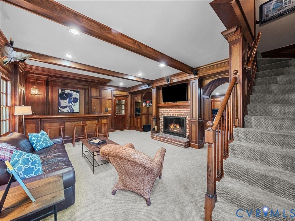 105 Running Cedar Lane, Countryside, Henrico, VA 23229 Wood-paneled walls with decorative wainscoting, exposed ceiling beams, brick-surround fireplace, custom built-in bar, and staircase featuring a wood handrail