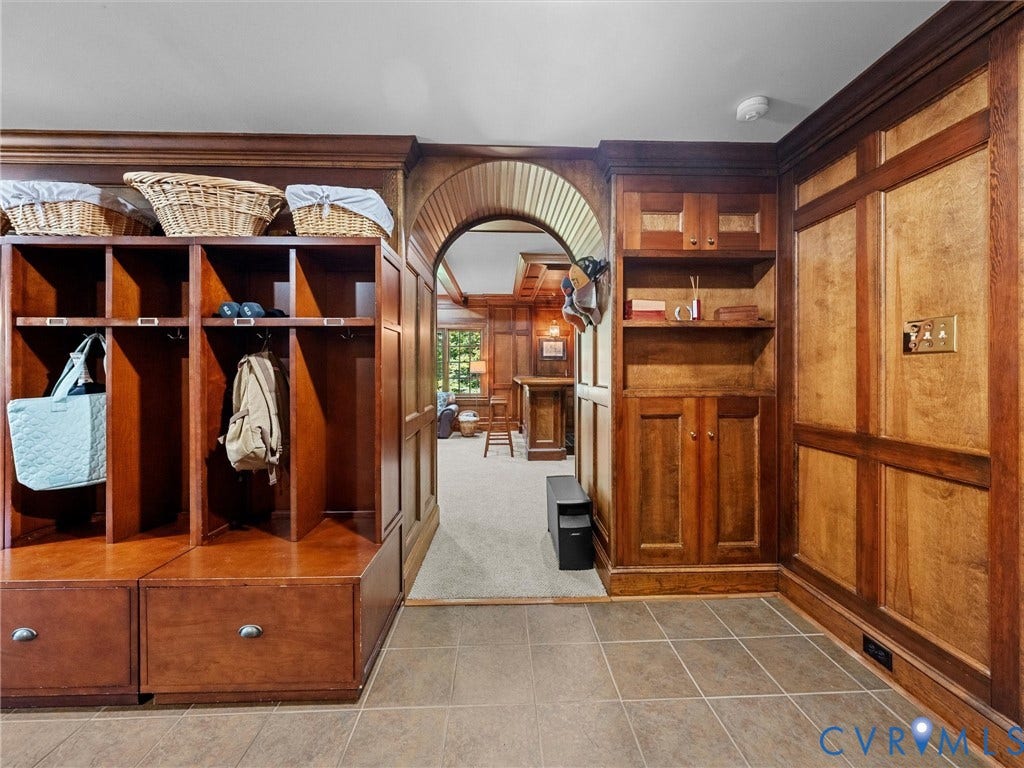 105 Running Cedar Lane, Countryside, Henrico, VA 23229 Custom wood-paneled wall cabinetry featuring integrated shelving, built-in storage lockers, and lower pull-out drawers, complemented by an arched architectural entryway and ceramic tile flooring