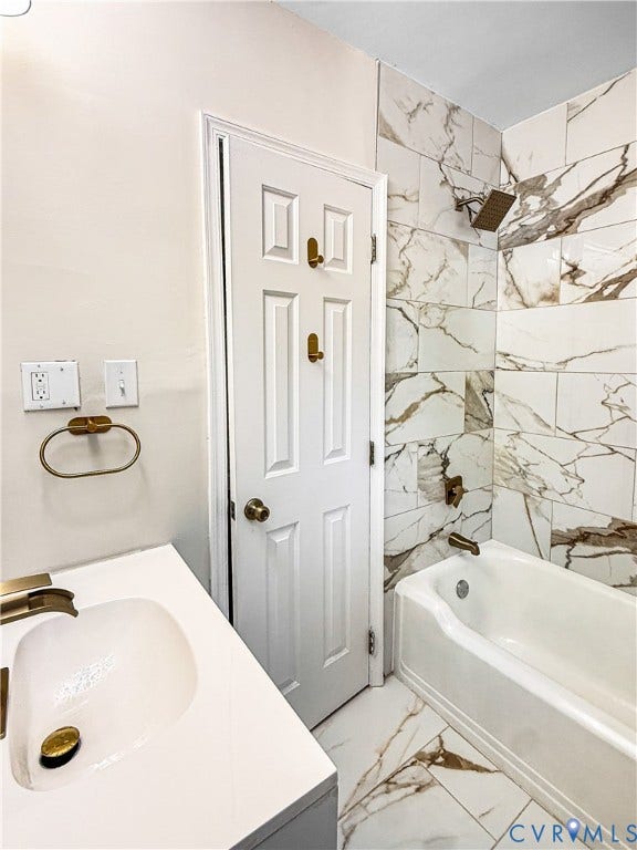 4003 Lee Boulevard, Dinwiddie, VA 23803 Bathroom featuring large-format decorative wall tile, a standard tub with brass-toned fixtures, a white vanity with an integrated sink, and coordinated brass-toned hardware