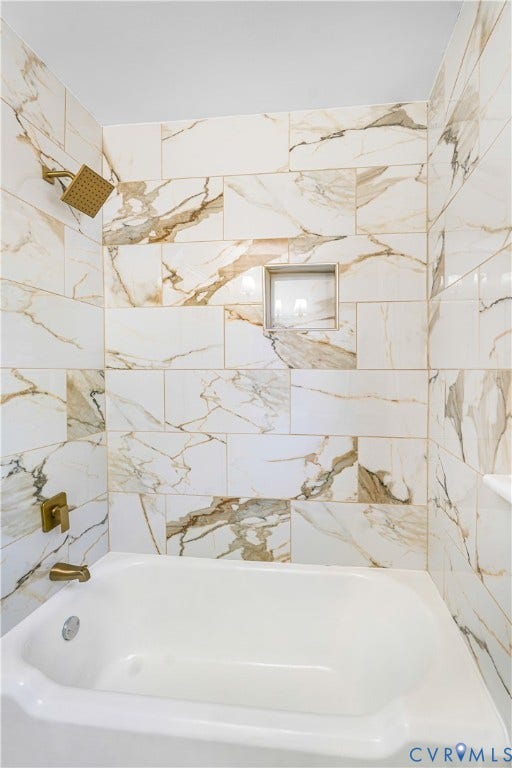 4003 Lee Boulevard, Dinwiddie, VA 23803 Shower and bathtub combination featuring large-format wall tile with veined patterning, gold-tone plumbing fixtures, and an integrated recessed soap niche