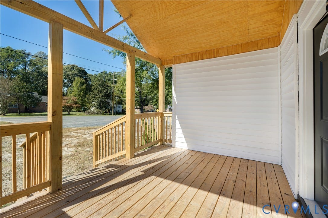 4003 Lee Boulevard, Dinwiddie, VA 23803 Covered front porch featuring exposed wood support beams, natural wood-finish decking, white horizontal siding, and wooden balustrade railings