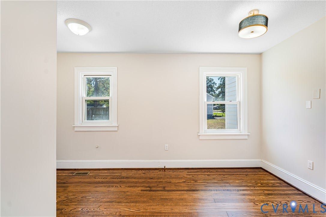 4003 Lee Boulevard, Dinwiddie, VA 23803 Room featuring wood-finish flooring, two double-hung windows with white trim, and overhead lighting fixtures