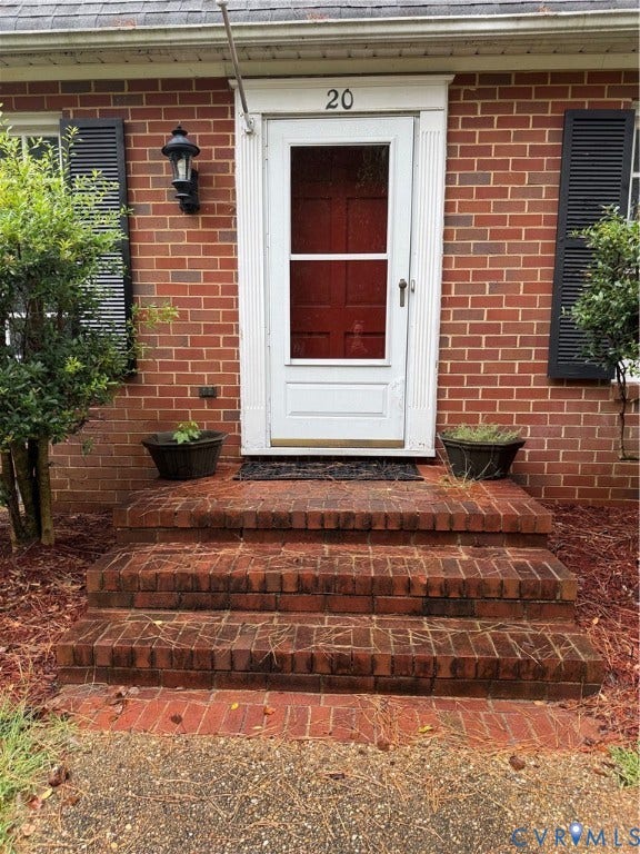 20 Jonquil Lane, Newport News, VA 23606 Brick exterior featuring a multi-step masonry stoop, white trim, classic louvered shutters, and a wall-mounted coach light