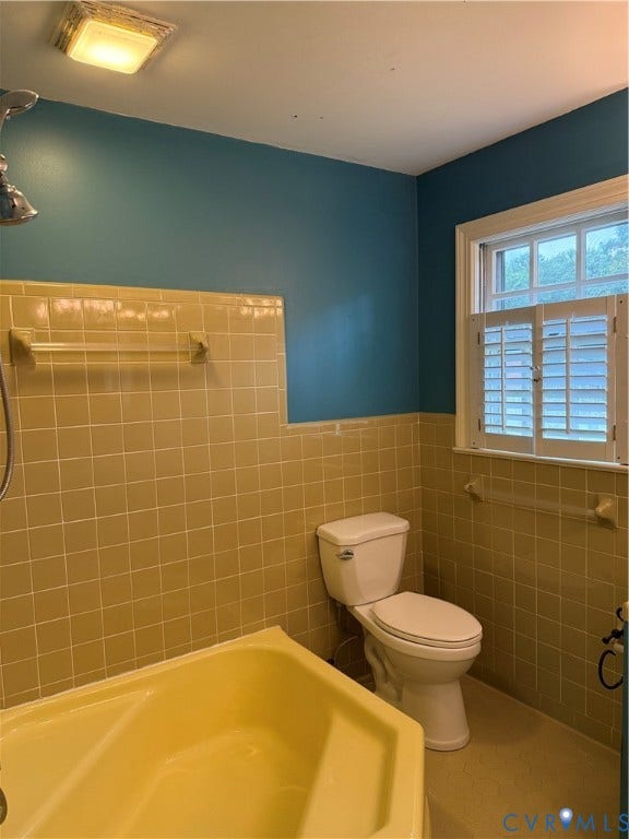 20 Jonquil Lane, Newport News, VA 23606 Bathroom featuring a soaking tub, ceramic tile wall surround, two-piece toilet, ceiling-mounted light fixture, and window with built-in shutters