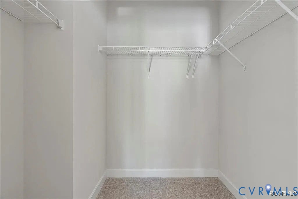 Walk-in closet featuring neutral carpeting and installed white wire shelving