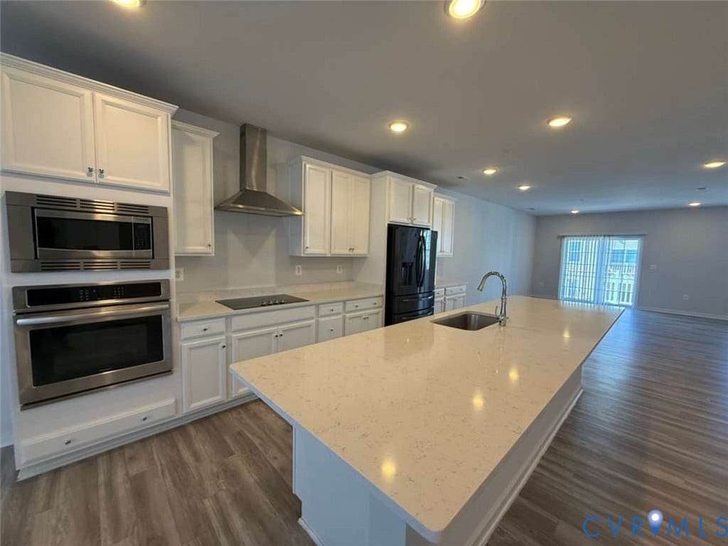 5912 Whitehurst Lane, #B, Henrico, VA 23227 Kitchen featuring white cabinetry, quartz countertops, a center island with an integrated sink, stainless steel wall-mounted oven and microwave, and wood-finish flooring