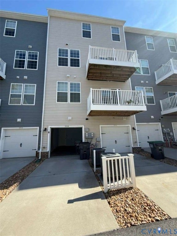 5912 Whitehurst Lane, #B, Henrico, VA 23227 Three-story townhome exterior featuring horizontal vinyl siding, private elevated balconies with white railings, and integrated garage parking