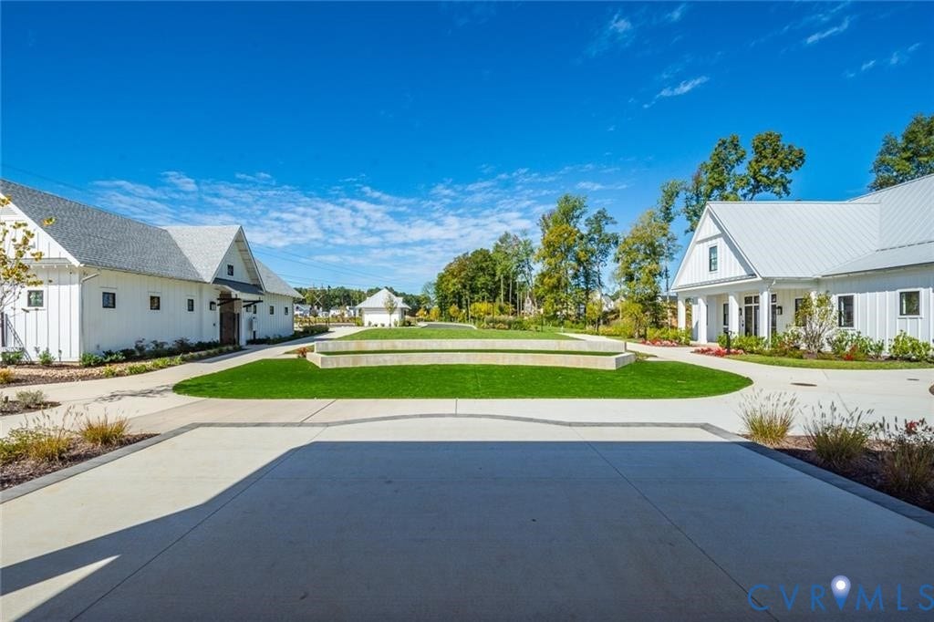 338 Hay Mill Alley, Glen Allen, VA 23060 Modern farmhouse-style exteriors with vertical siding and metal roofing, central manicured lawn, stone retaining wall, and expansive paved courtyard