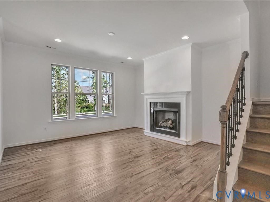 338 Hay Mill Alley, Glen Allen, VA 23060 Living area featuring wood-finish flooring, recessed lighting, a fireplace with a white mantel, and a staircase with a wooden handrail and metal balusters
