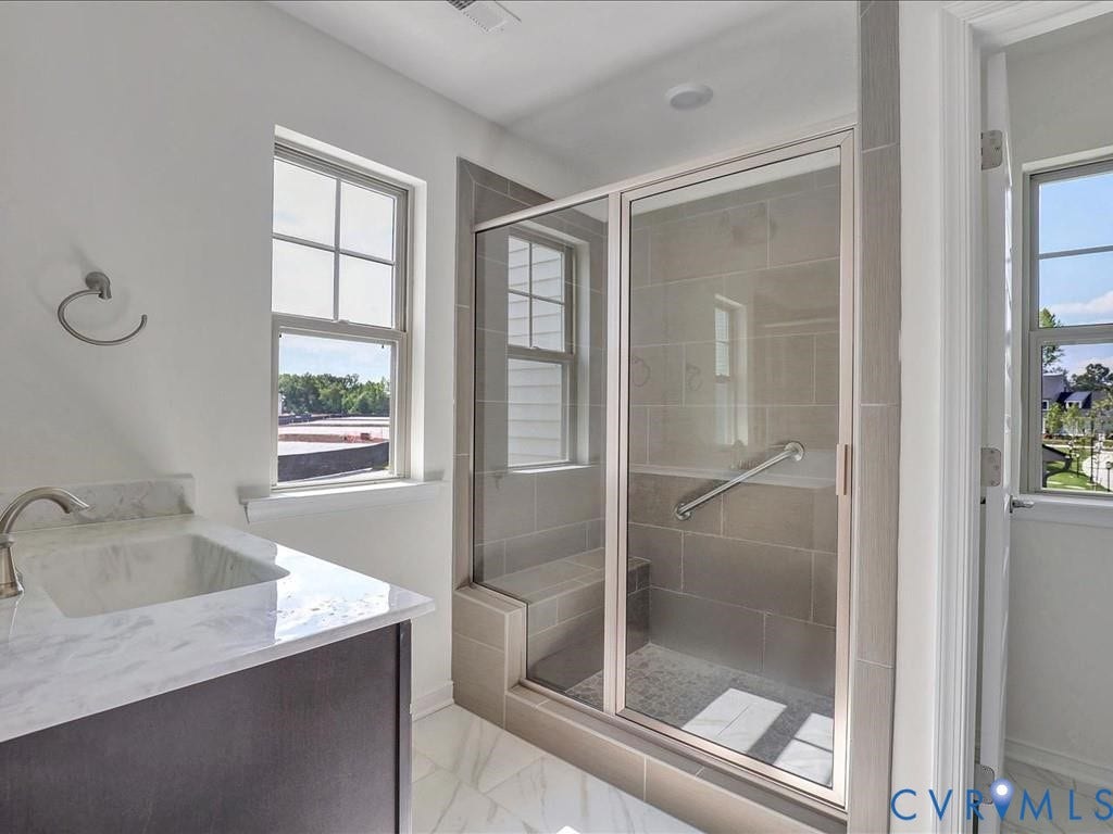 338 Hay Mill Alley, Glen Allen, VA 23060 Vanity with stone-surface countertop, under-mount sink, chrome faucet, tiled walk-in shower with integrated bench and glass enclosure, and windows with multi-pane glazing