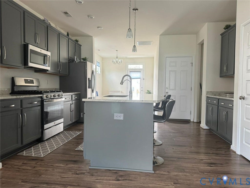 338 Hay Mill Alley, Glen Allen, VA 23060 Kitchen featuring dark cabinetry, stone-finish countertops, stainless steel appliances, a central island with an integrated sink, and wood-finish flooring