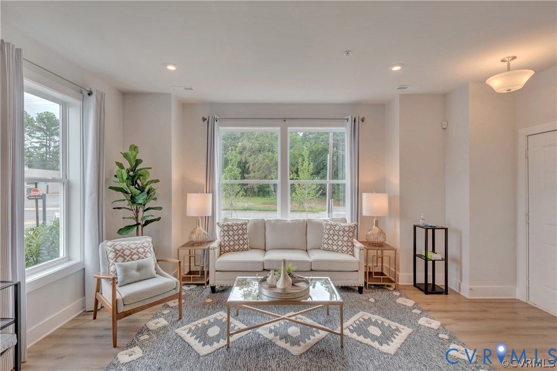 Living area featuring wood-finish flooring, recessed lighting, neutral wall paint, and expansive windows