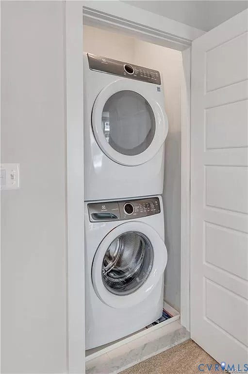Stacked front-loading washer and dryer set enclosed within a dedicated closet featuring a multi-panel door