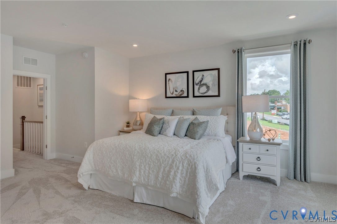 Neutral-toned carpet, recessed lighting, and large window with natural light
