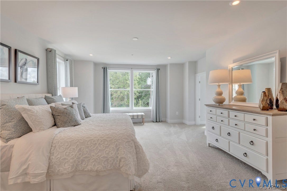 Neutral wall-to-wall carpeting, recessed ceiling lighting, and large windows with natural illumination