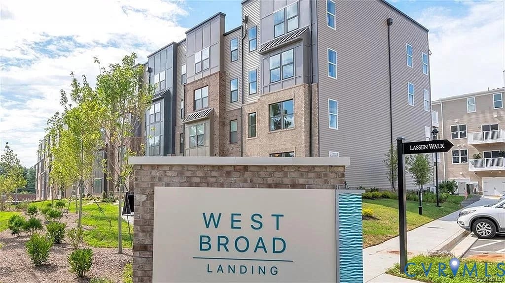 Multi-story exterior featuring a mix of brick and siding facades, metal panel accents, and a landscaped grounds area with mature trees and shrubbery