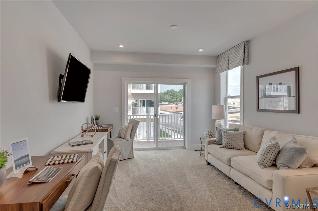 Neutral-toned carpeted flooring, recessed lighting, and glass sliding doors leading to an outdoor balcony