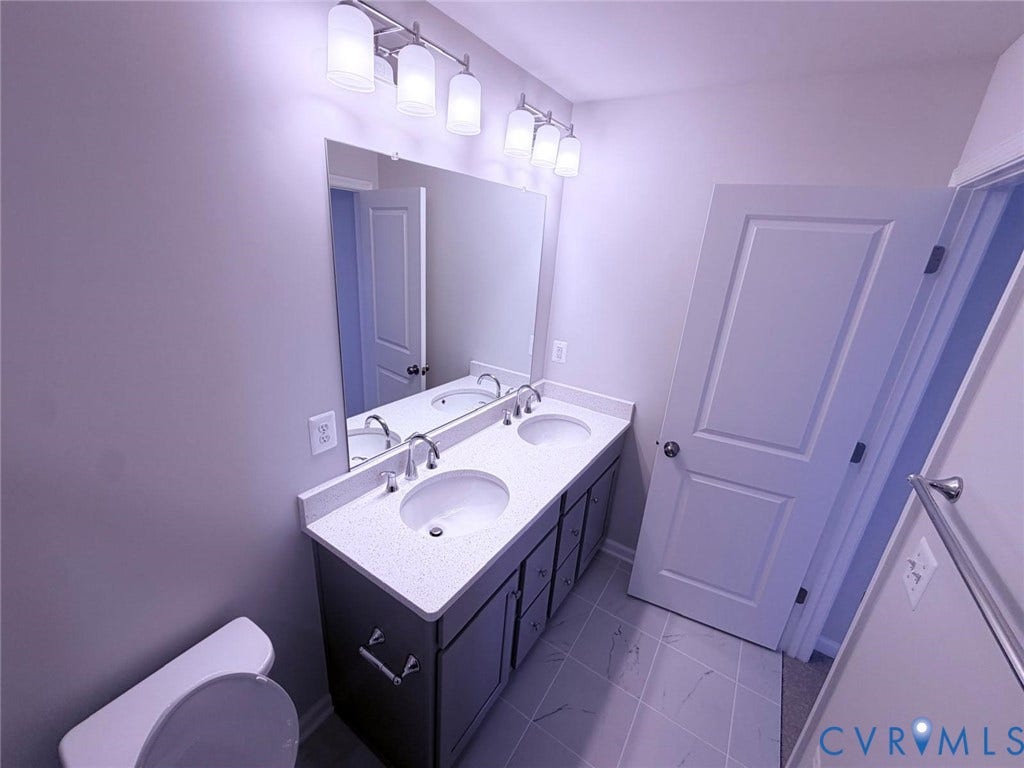 504 Sybil Street, Glen Allen, VA 23060 Double vanity featuring a light-toned countertop with integrated dual basins, dark cabinetry, large wall-mounted mirror, and tile flooring