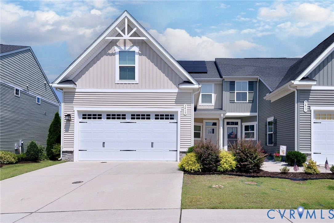 3415 Foxglove Drive, Toano, VA 23168 Multi-story exterior featuring lap and vertical siding, a two-car garage with carriage-style doors, asphalt shingle roofing, integrated solar panels, and a concrete driveway
