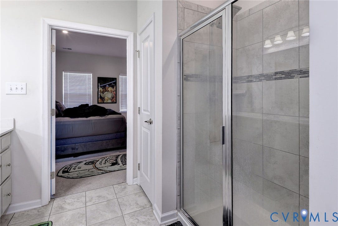 3415 Foxglove Drive, Toano, VA 23168 Walk-in shower featuring glass enclosure, large-format tile surround, and decorative glass mosaic accent tile, complemented by ceramic tile flooring