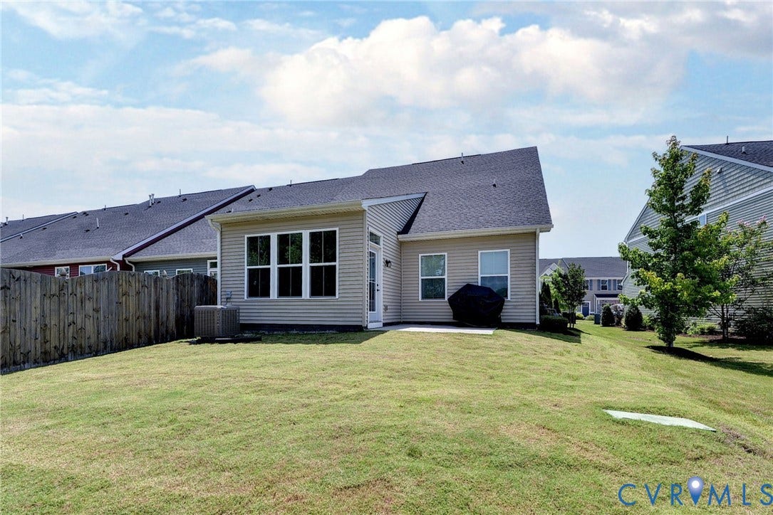 3415 Foxglove Drive, Toano, VA 23168 Rear exterior featuring light-toned horizontal siding, dark shingle roofing, multi-pane windows, and a fenced-in grassy yard