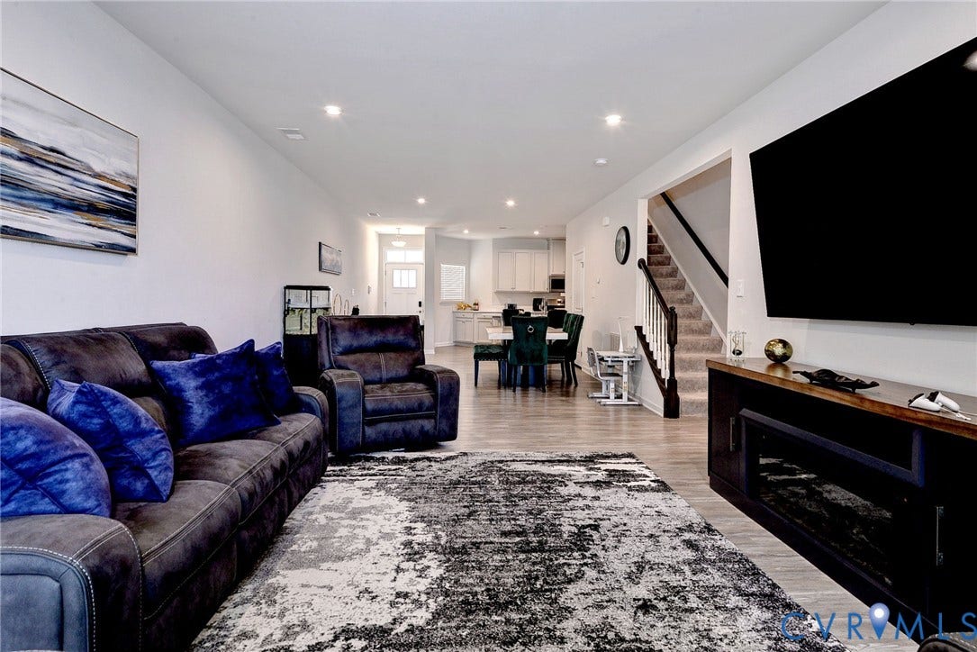 3415 Foxglove Drive, Toano, VA 23168 Neutral interior featuring wood-finish flooring, recessed lighting, a built-in electric fireplace console, and a staircase with a wooden handrail and balusters