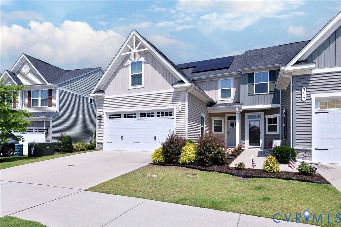 3415 Foxglove Drive, Toano, VA 23168 Two-story residence featuring horizontal siding, gable rooflines, solar panels, and an attached multi-car garage with carriage-style hardware
