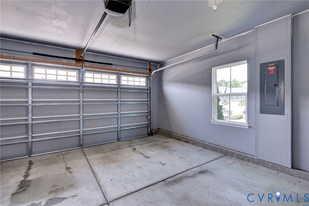 3415 Foxglove Drive, Toano, VA 23168 Garage featuring a sectional overhead door with paneled windows, interior window with grid muntins, and a wall-mounted electrical panel