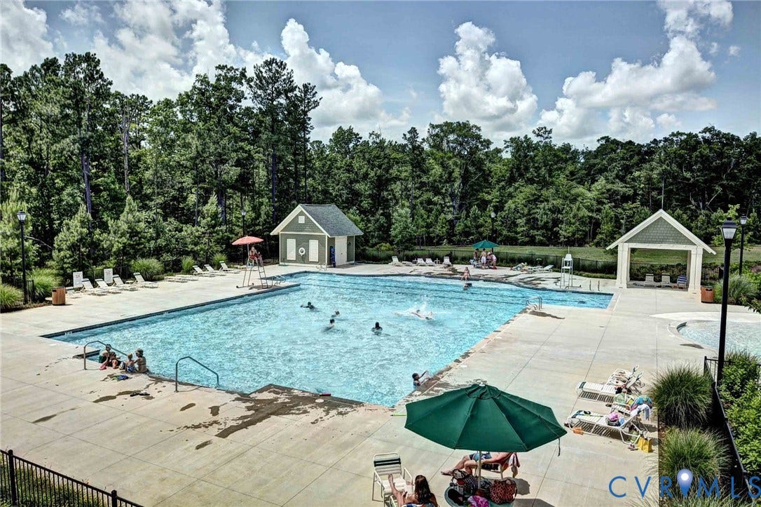 3415 Foxglove Drive, Toano, VA 23168 Swimming pool featuring concrete decking, a surrounding metal fence, and two covered structures