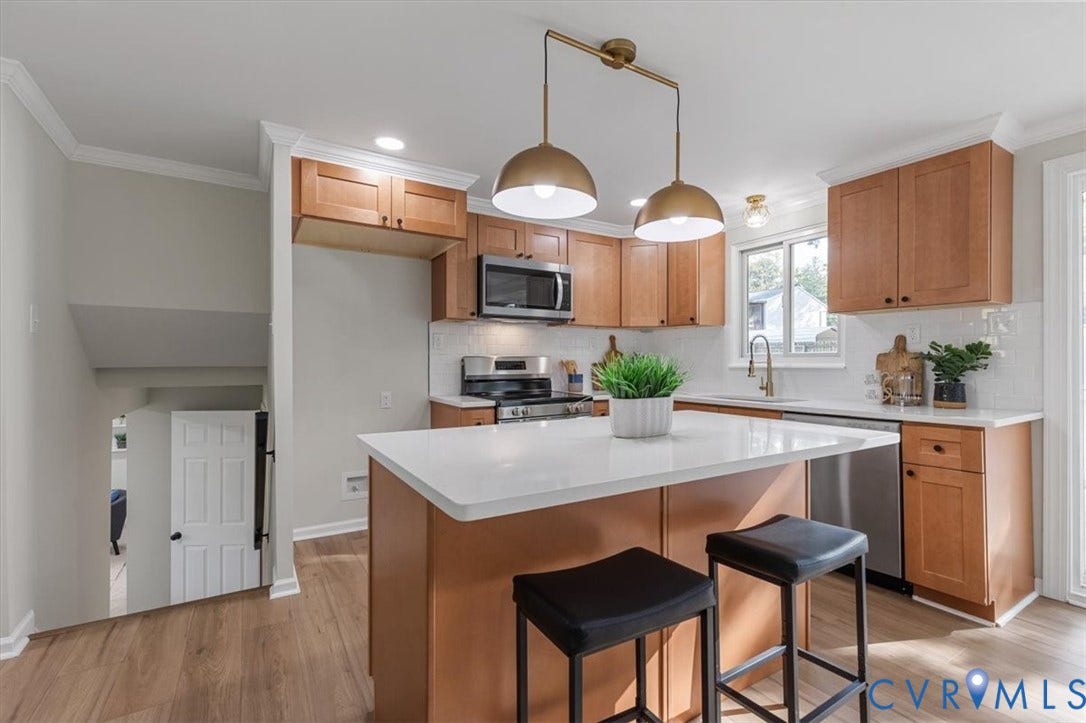 9201 Packard Court, Glen Allen, VA 23060 Kitchen featuring light wood-finish cabinetry, a white countertop island, stainless steel appliances, a white subway tile backsplash, and dual-pendant brass lighting