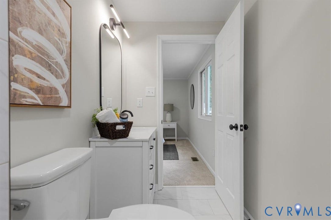 9201 Packard Court, Glen Allen, VA 23060 White vanity cabinet with integrated countertop, arched wall-mounted mirror, minimalist light fixture, and tile flooring
