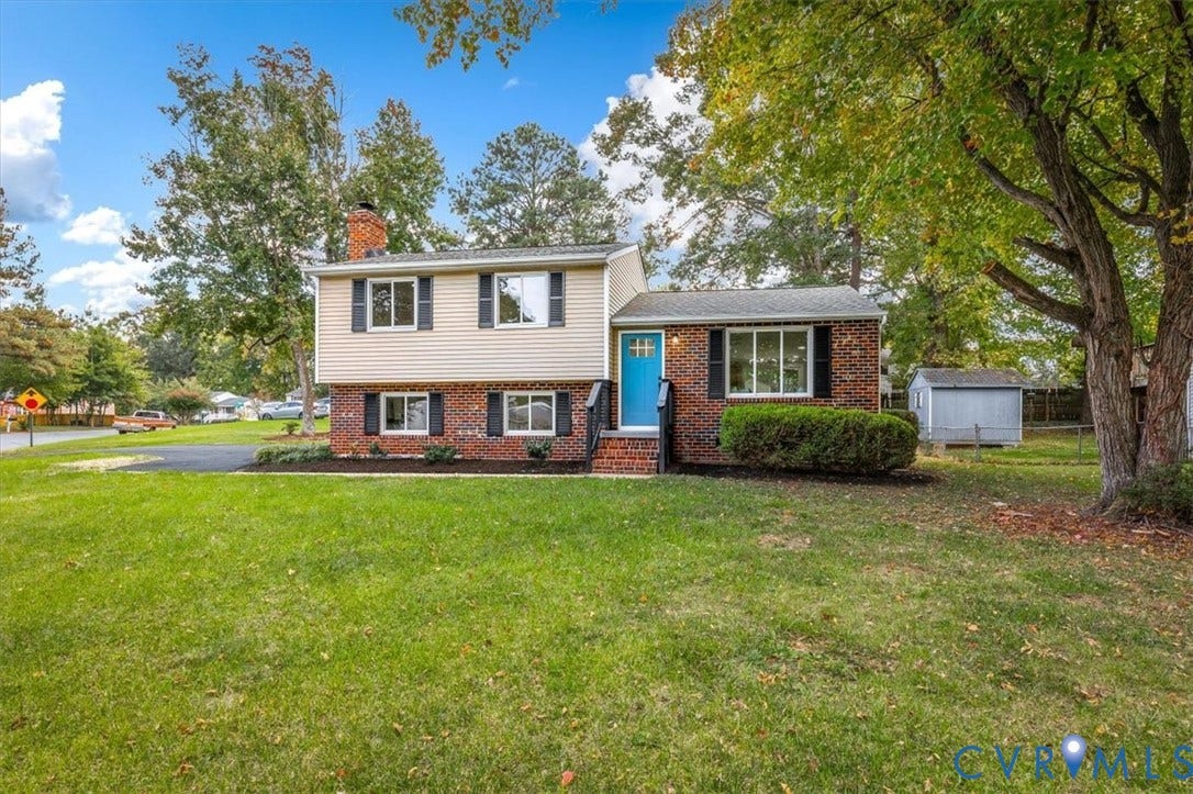 9201 Packard Court, Glen Allen, VA 23060 Split-level exterior featuring a brick and vinyl siding faade, chimney, asphalt driveway, and detached storage structure on a manicured lawn