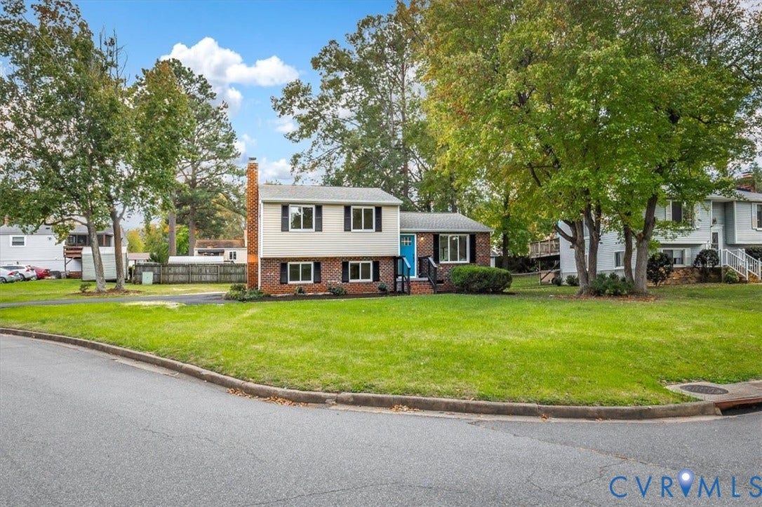 9201 Packard Court, Glen Allen, VA 23060 Split-level exterior featuring a brick and siding facade, a side-profile chimney, multi-pane windows with shutters, and a lawn with mature trees