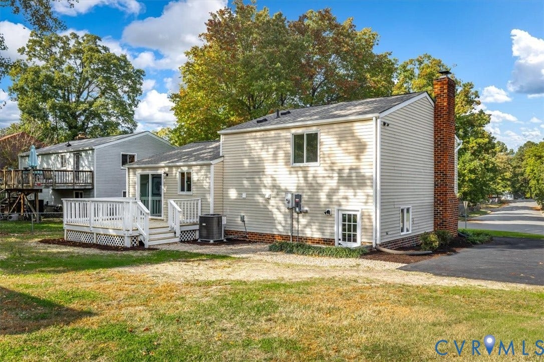 9201 Packard Court, Glen Allen, VA 23060 Exterior featuring light-toned horizontal siding, a raised wood deck with white lattice skirting, a classic red brick chimney, and an asphalt driveway