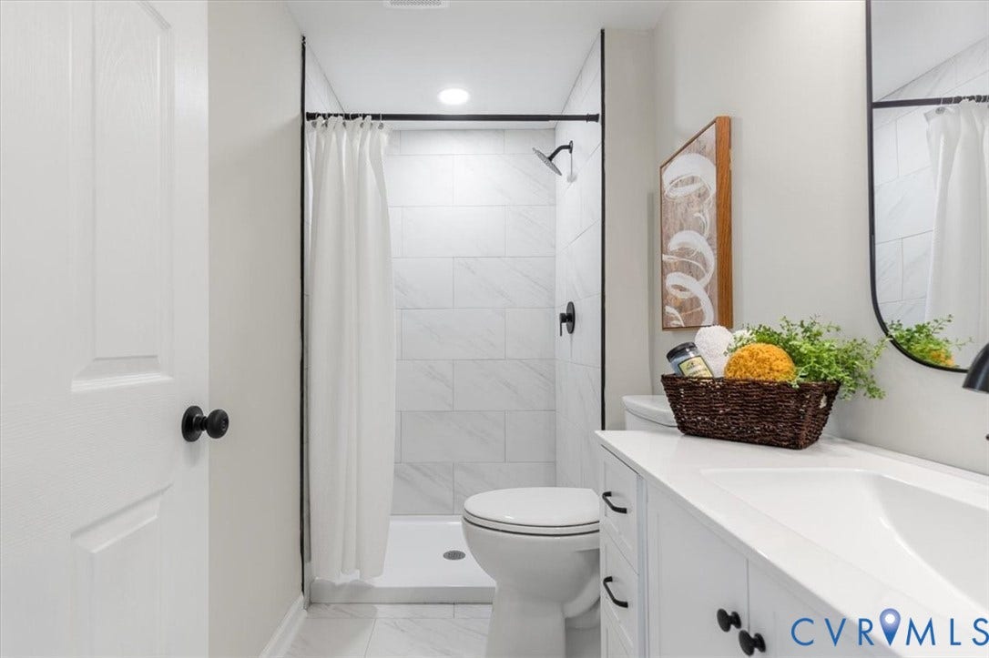 9201 Packard Court, Glen Allen, VA 23060 Bathroom featuring a white vanity cabinet with a stone-top integrated sink, matte black hardware, a tiled walk-in shower with black metal trim, and large-format tile flooring