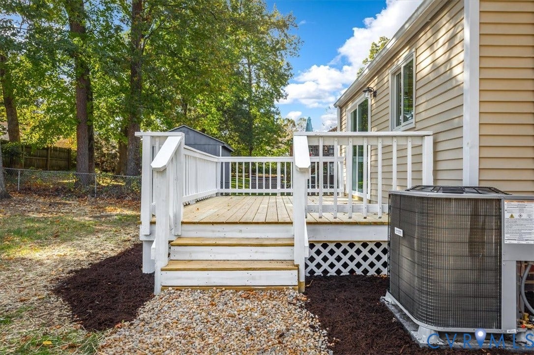 9201 Packard Court, Glen Allen, VA 23060 Exterior wood deck featuring white railing and lattice skirting, gravel walkway, vinyl siding, and mature trees