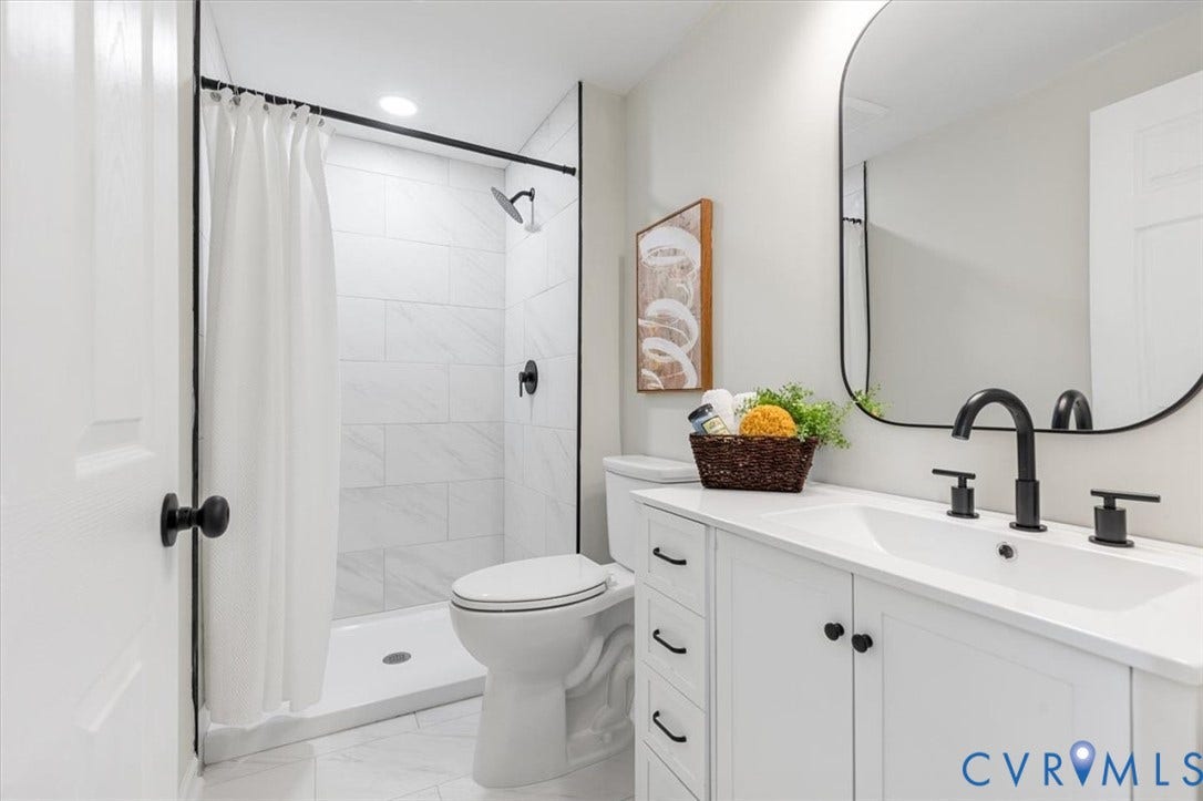 9201 Packard Court, Glen Allen, VA 23060 Bathroom featuring a white vanity with drawers, a rectangular undermount sink, a matte black widespread faucet, a wall-mounted arched mirror, and a walk-in shower with white tile surround and matte black fixtures